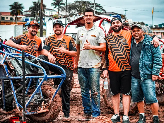 Equipe de pilotos reunida ao lado da gaiola